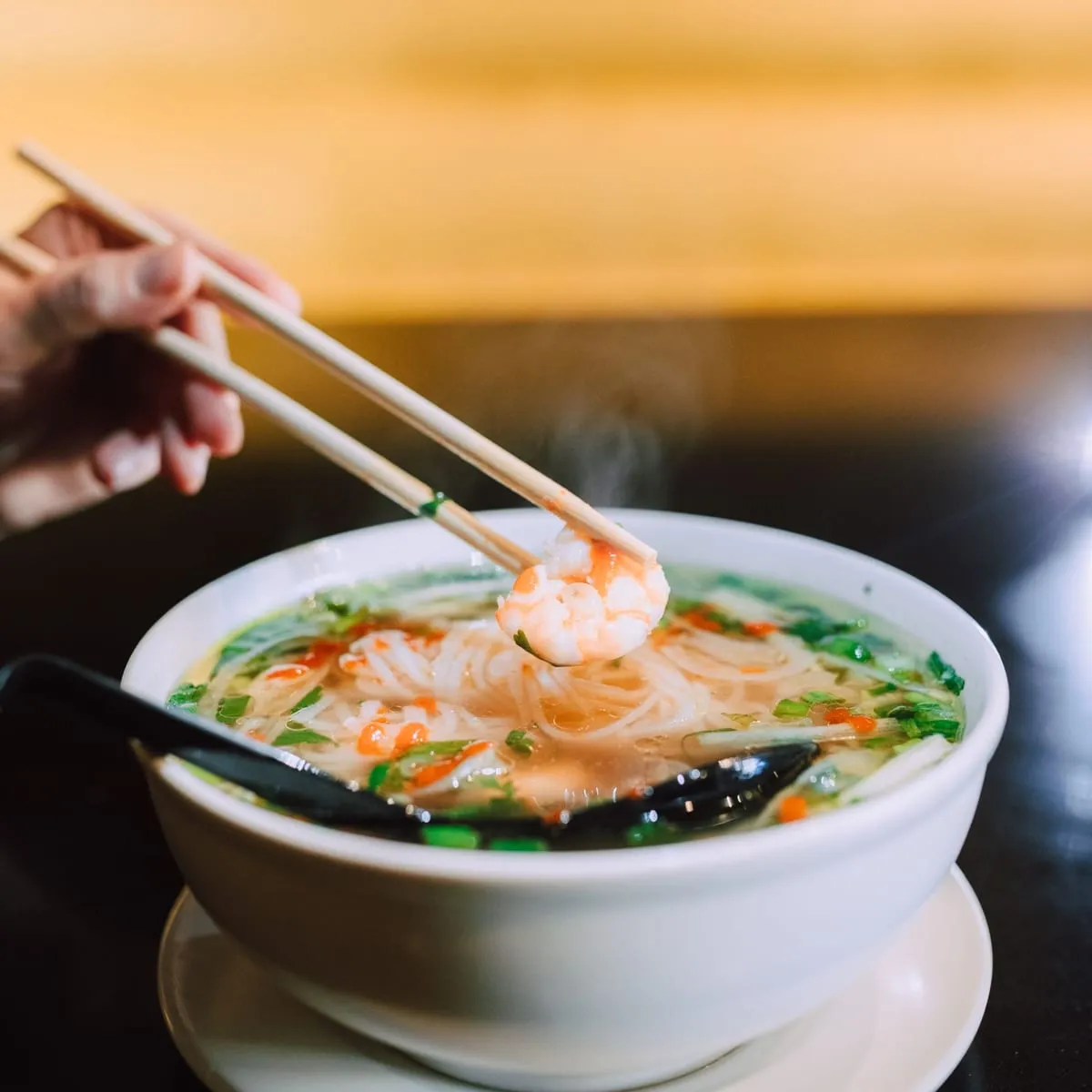 Sopa wantán con langostino y verduras en tazón blanco